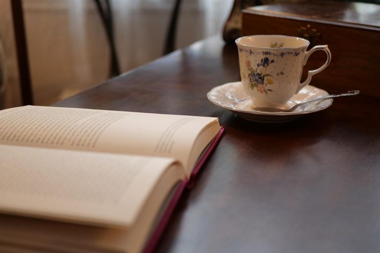 Symbolfoto zeigt eine Tee-Tasse neben einem aufgeschlagenen Buch