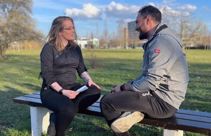 Zwei Personen sitzen im Park auf einer Bank und sprechen miteinander, im Rahmen der Living Library von Jedermensch e.V.
