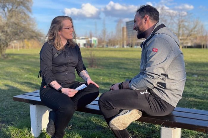 Zwei Personen sitzen im Park auf einer Bank und sprechen miteinander, im Rahmen der Living Library von Jedermensch e.V.