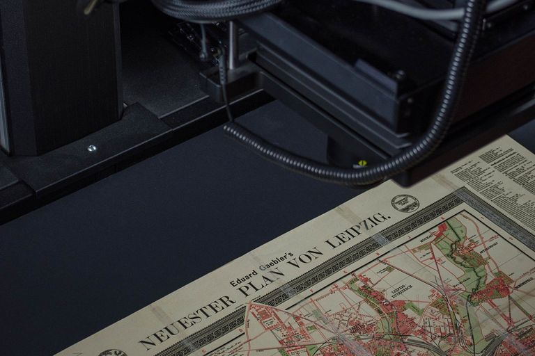 Ein Scanner liest einen historischen Stadtplan mit dem Titel "Neuester Plan von Leipzig" ein.
