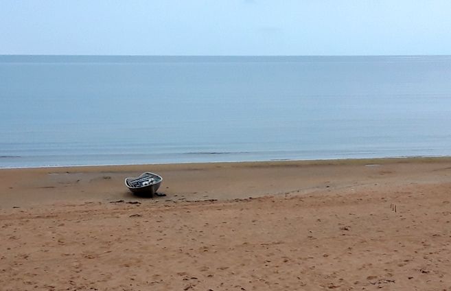 Symbolfoto von einem Ruderboot an einem leeren Sandstrand.