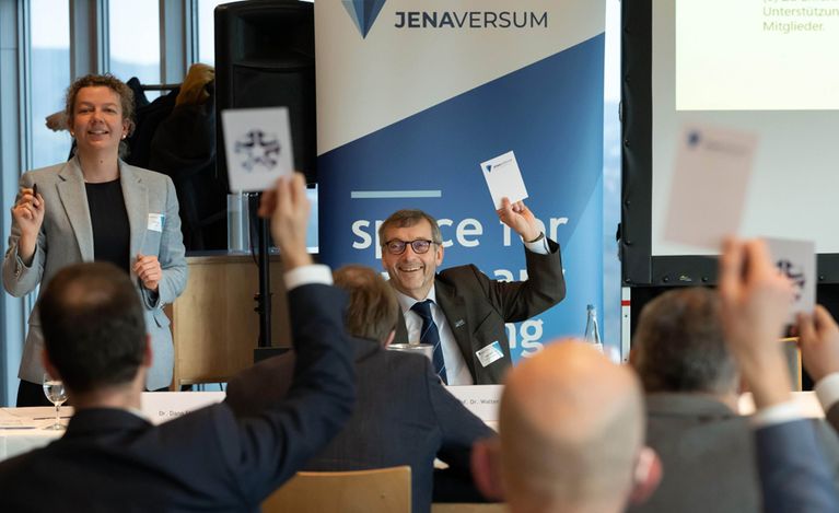 Foto von der Auftakt-Veranstaltung des Netzwerks JenaVersum mit Dana Strauß und dem Präsidenten der Uni Jena, Walter Rosenthal, sowie sitzenden Gästen.
